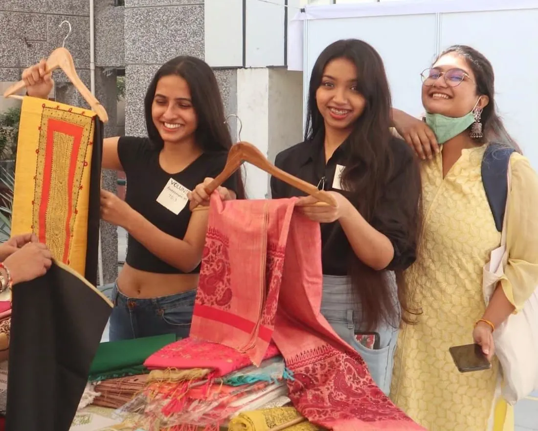 Visitors holding up handwoven textiles