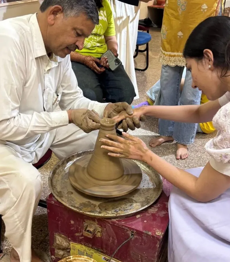 Artisan guiding a participant at the potter's wheel